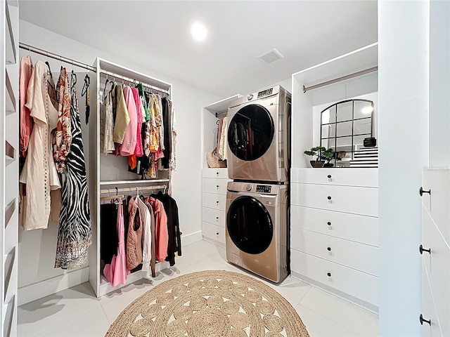 laundry room featuring light tile patterned flooring, stacked washer and clothes dryer, visible vents, and laundry area