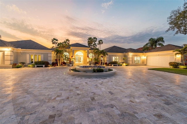 view of front of home featuring stucco siding, curved driveway, and an attached garage