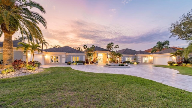 view of front of home with a front yard, an attached garage, and curved driveway