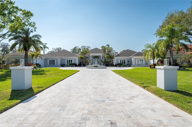 view of front of house with curved driveway, french doors, and a front lawn