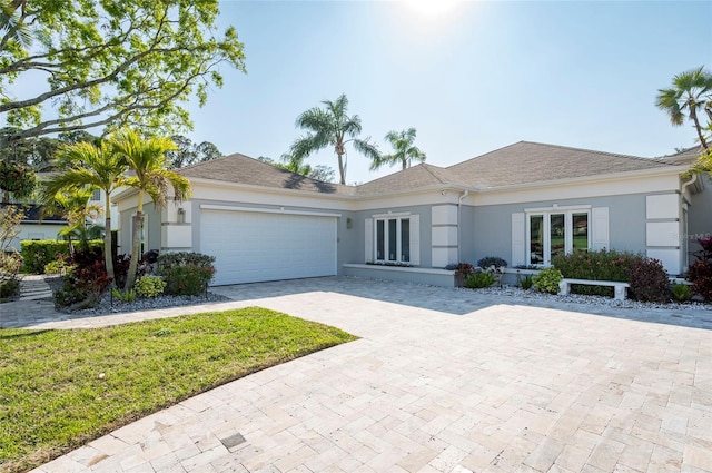 ranch-style home featuring stucco siding, decorative driveway, and an attached garage