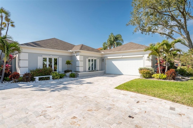 ranch-style house featuring an attached garage, driveway, and stucco siding