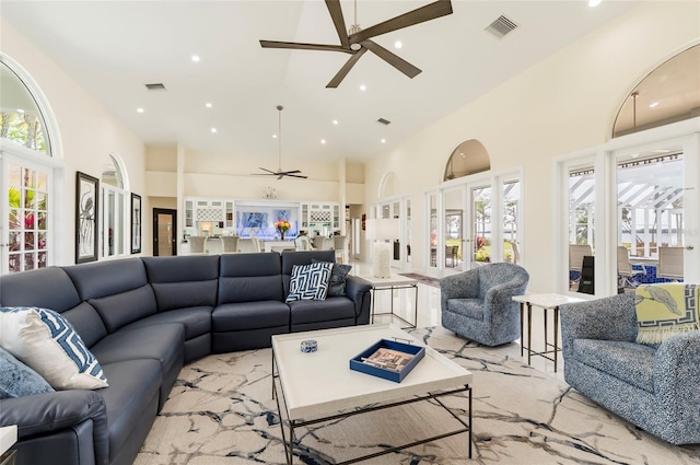 living area featuring a high ceiling, a ceiling fan, and visible vents