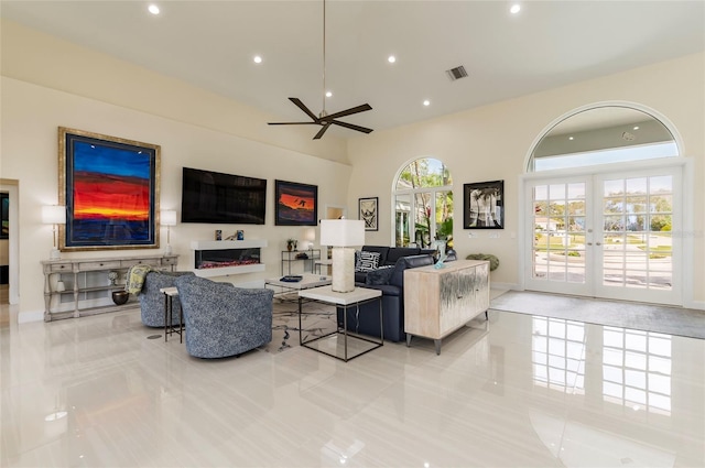 living area with visible vents, recessed lighting, ceiling fan, french doors, and a towering ceiling