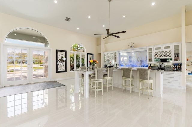 kitchen with white cabinetry, a ceiling fan, visible vents, and light stone countertops