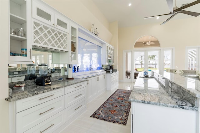 kitchen with a wealth of natural light, light stone countertops, a spacious island, and white cabinetry