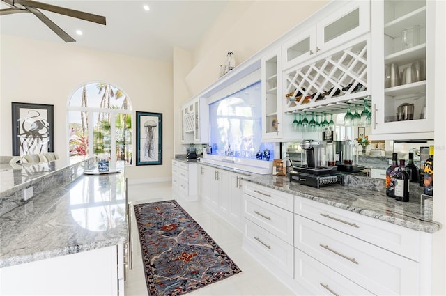 kitchen with a wealth of natural light, white cabinets, and light stone countertops