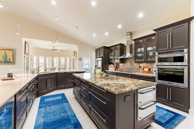 kitchen featuring a warming drawer, plenty of natural light, wall chimney exhaust hood, and a sink