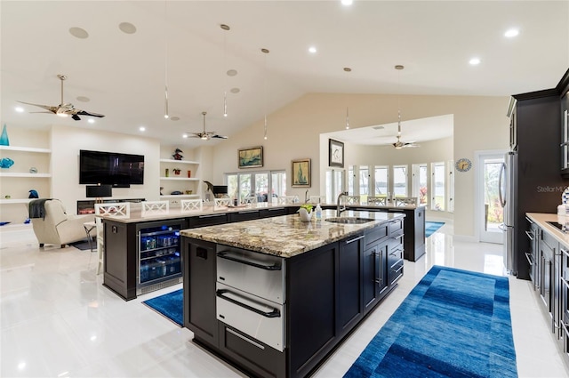 kitchen featuring beverage cooler, a ceiling fan, a sink, a large island, and a warming drawer