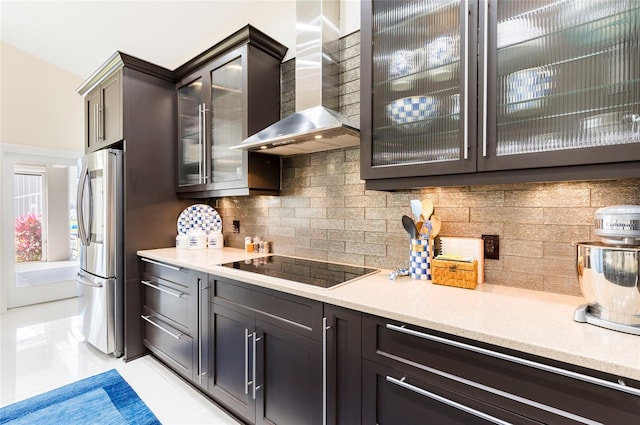 kitchen with black electric stovetop, light countertops, smart refrigerator, wall chimney range hood, and tasteful backsplash