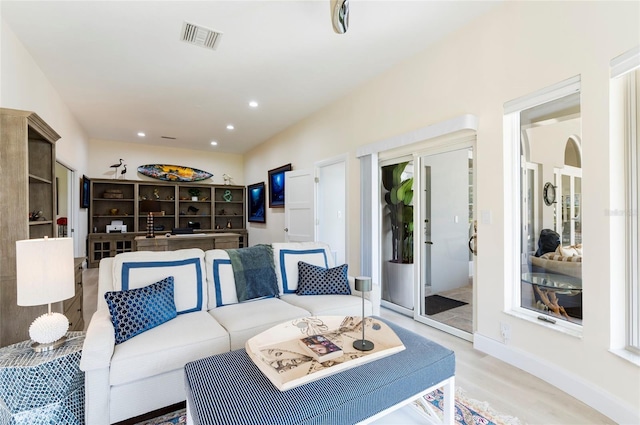 living room featuring baseboards, visible vents, recessed lighting, arched walkways, and light wood-type flooring