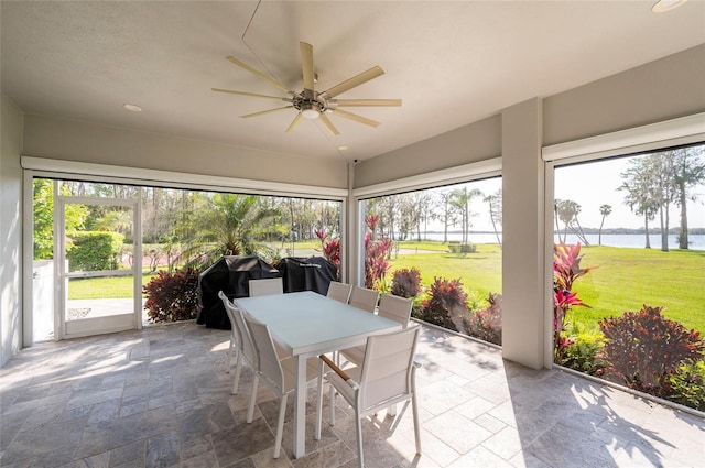 sunroom / solarium with ceiling fan and a water view