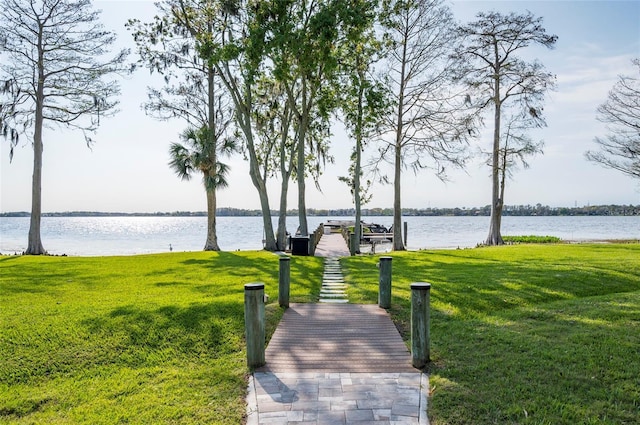 surrounding community with a yard, a water view, and a boat dock