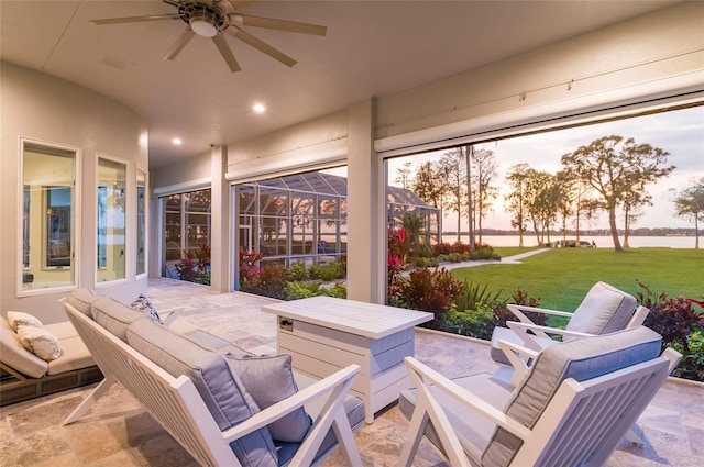 patio terrace at dusk with an outdoor living space, a lawn, and a ceiling fan