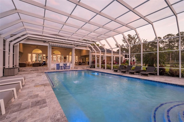 outdoor pool with glass enclosure, outdoor lounge area, and a patio area