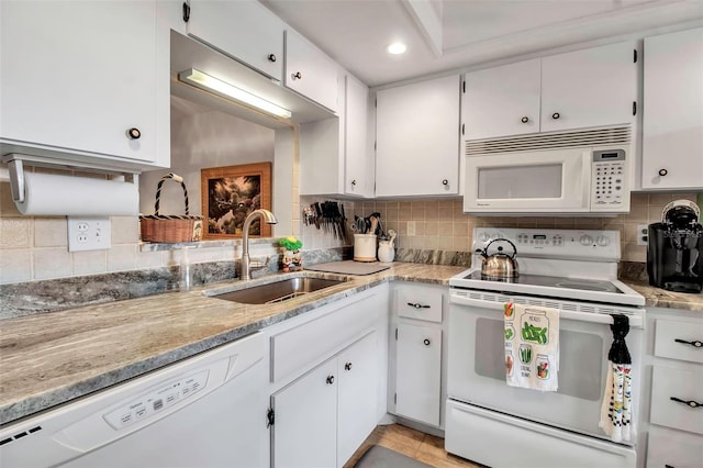 kitchen with a sink, white appliances, backsplash, and white cabinetry