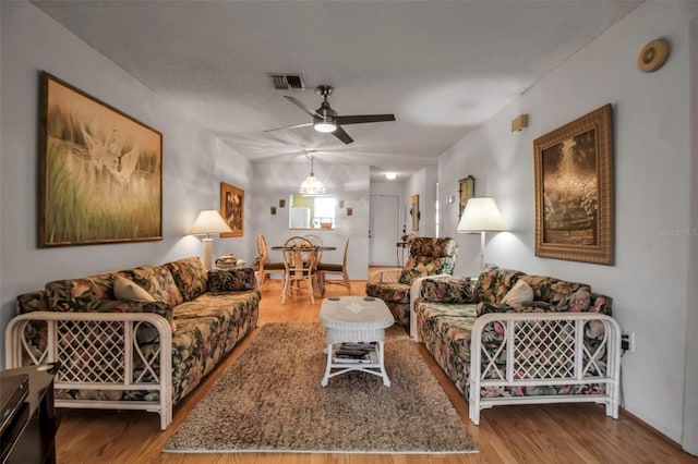 living area featuring visible vents, a ceiling fan, and wood finished floors