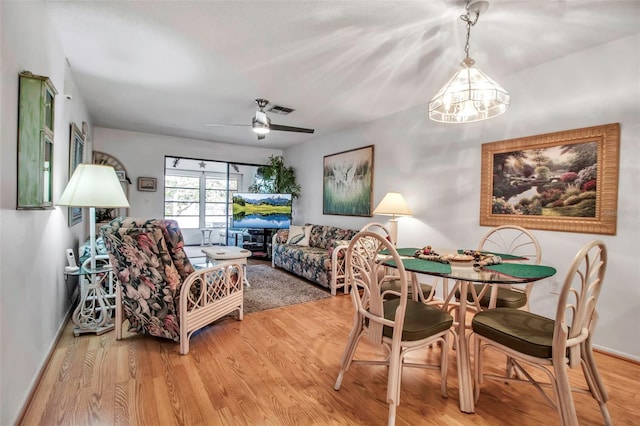 dining space featuring light wood-type flooring, visible vents, baseboards, and ceiling fan with notable chandelier