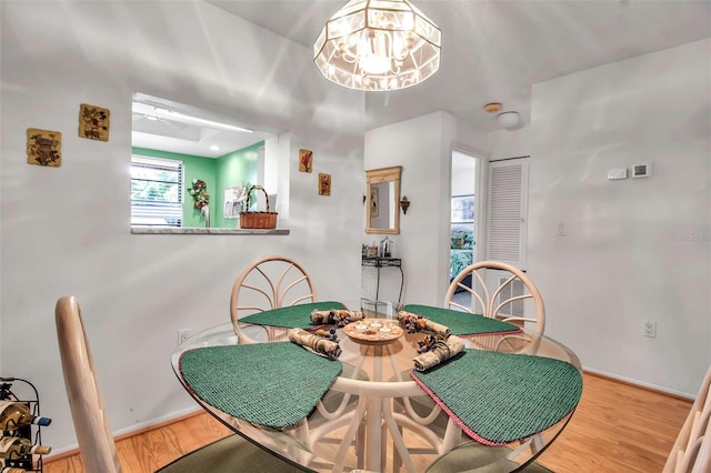 dining room with a notable chandelier, baseboards, and wood finished floors