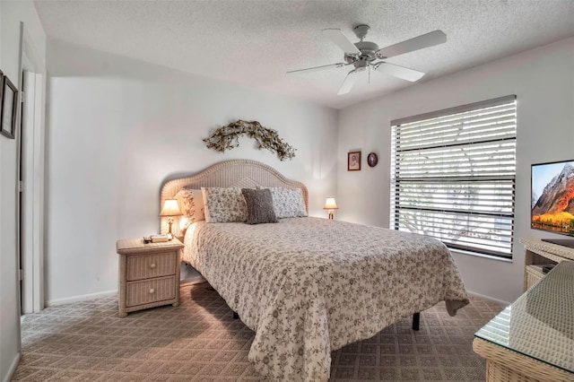 bedroom with baseboards, a textured ceiling, a ceiling fan, and dark colored carpet