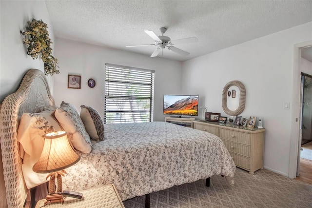 bedroom with baseboards, light carpet, a textured ceiling, and a ceiling fan