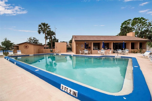 community pool with fence and a patio area