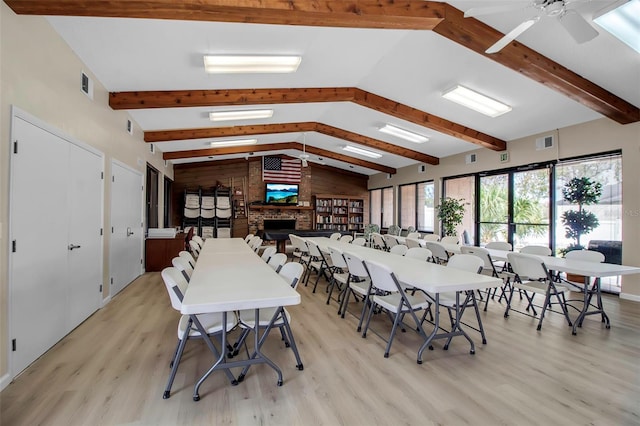 dining room featuring visible vents, light wood-style flooring, vaulted ceiling with beams, and a ceiling fan