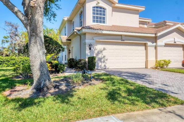 view of front of house featuring stucco siding, a tile roof, decorative driveway, and a garage