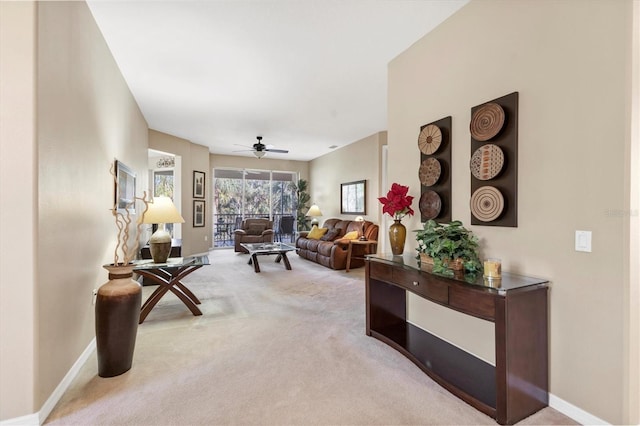 living room with baseboards, light carpet, and ceiling fan