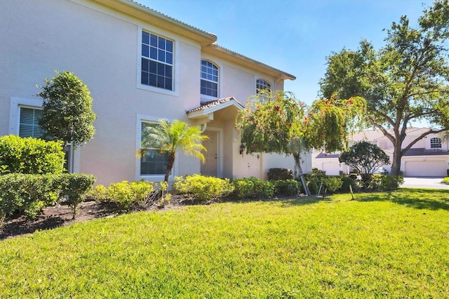 view of front facade featuring stucco siding, a tile roof, and a front lawn