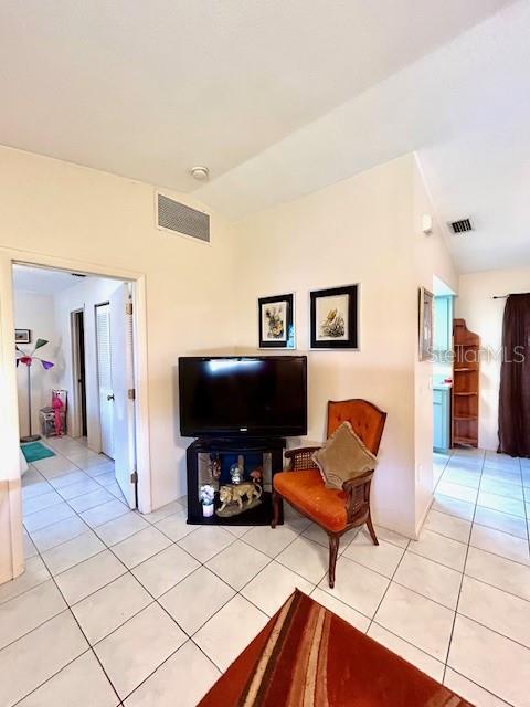 living area with lofted ceiling, light tile patterned flooring, and visible vents