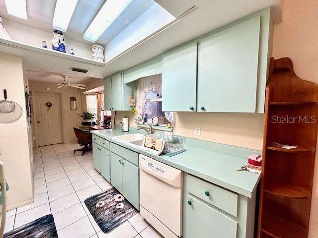 kitchen with light tile patterned floors, white dishwasher, a skylight, and light countertops