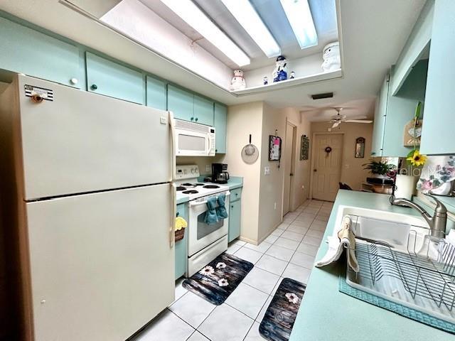 kitchen with light tile patterned floors, ceiling fan, white appliances, visible vents, and light countertops