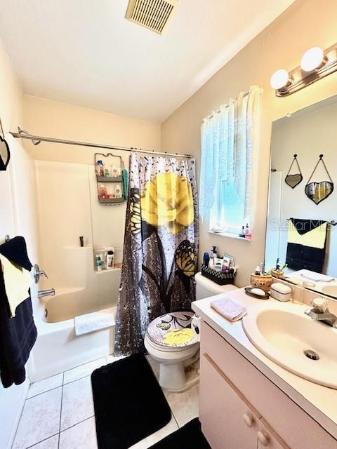 full bathroom featuring toilet, shower / tub combo, vanity, visible vents, and tile patterned floors