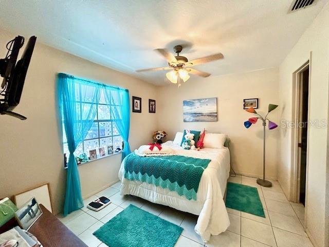 bedroom with tile patterned flooring, visible vents, and ceiling fan