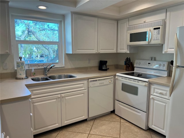 kitchen with a sink, white appliances, white cabinets, light countertops, and light tile patterned floors