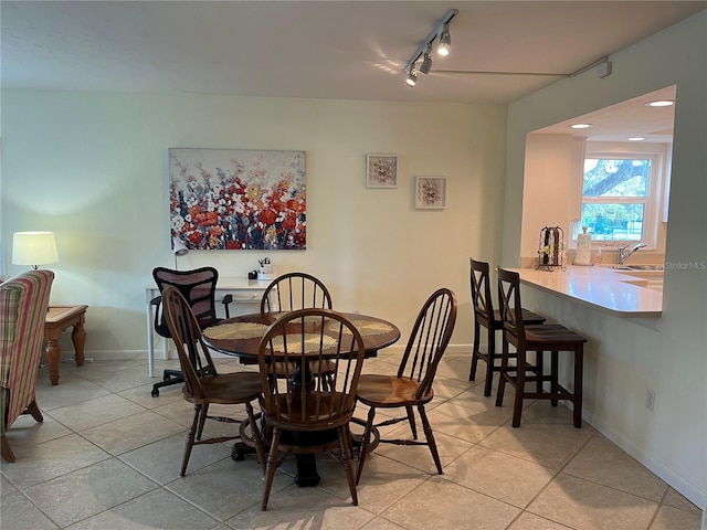 dining room featuring baseboards, light tile patterned flooring, and track lighting