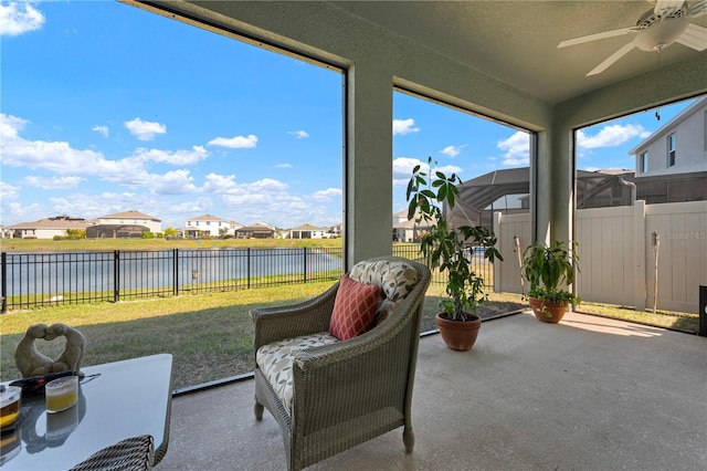 sunroom / solarium featuring a residential view, ceiling fan, and a water view