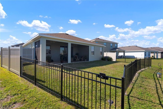 rear view of house featuring a yard, a sunroom, a fenced backyard, and stucco siding