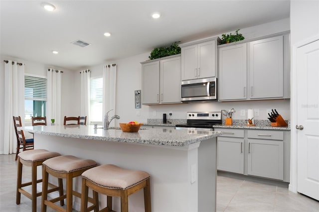 kitchen featuring a kitchen bar, visible vents, gray cabinets, recessed lighting, and stainless steel appliances