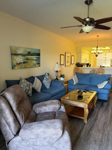 living room featuring ceiling fan with notable chandelier, vaulted ceiling, a textured ceiling, and wood finished floors