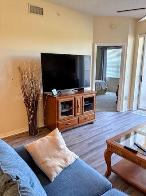 living area featuring wood finished floors, visible vents, and baseboards