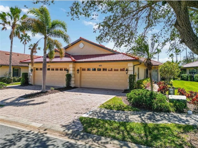 view of front of house featuring stucco siding, a tile roof, decorative driveway, and a garage