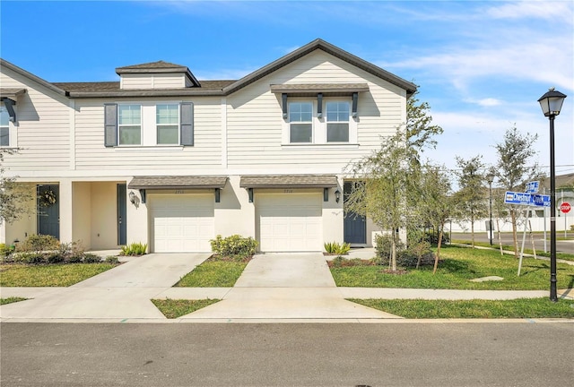 multi unit property featuring a garage, concrete driveway, and a front yard