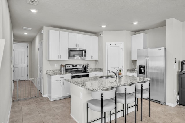 kitchen with a sink, white cabinets, an island with sink, and stainless steel appliances