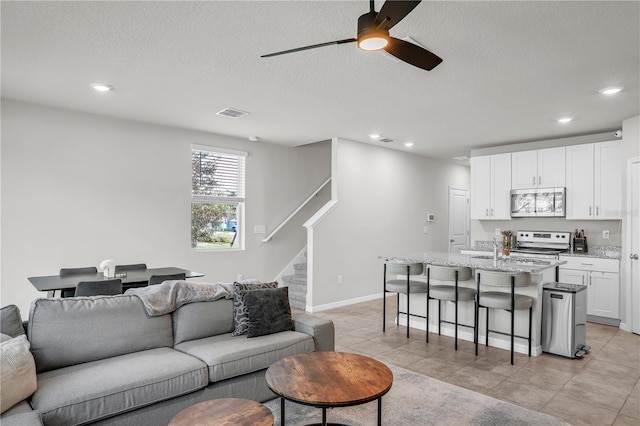 living room featuring visible vents, a textured ceiling, recessed lighting, stairway, and light tile patterned floors