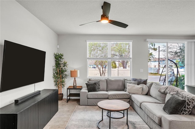 living area featuring light tile patterned floors, a textured ceiling, and ceiling fan