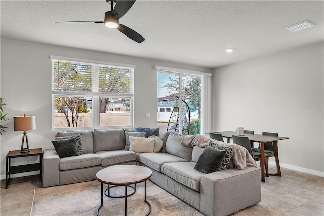 living room with visible vents, baseboards, a textured ceiling, and a ceiling fan