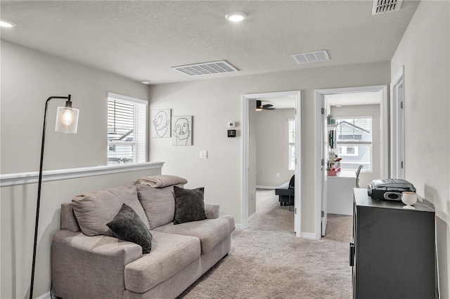 living room with visible vents, light colored carpet, and plenty of natural light