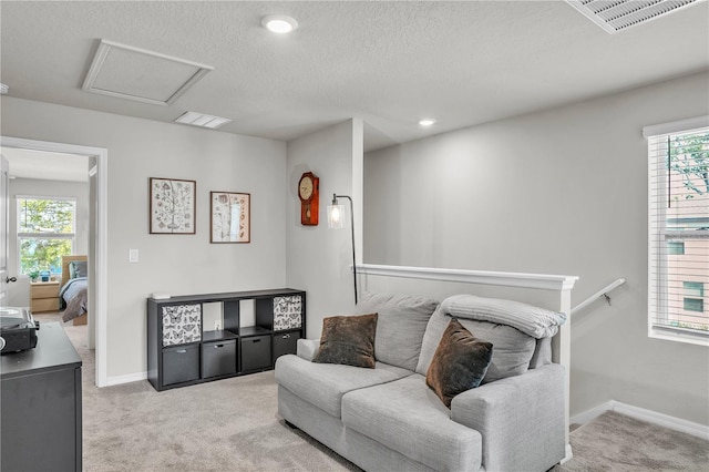 living room featuring visible vents, baseboards, light colored carpet, and attic access